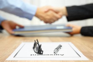 businessman and businesswoman are shaking hands and exchanging folder